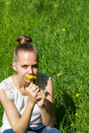 Girl sitting on the grass with dandelions in handsの写真素材