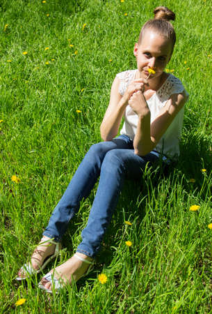 Girl sitting on the grass with dandelion in handの写真素材