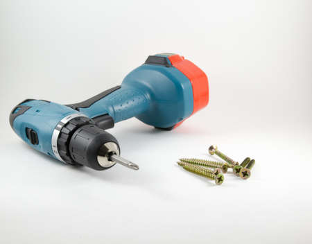 Cordless screwdriver and screws on a white background