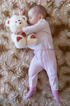 Newborn baby sleeps with a teddy bearの写真素材