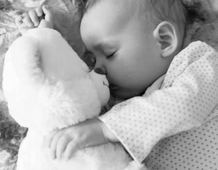 Newborn baby sleeps with a teddy bear black and whiteの写真素材