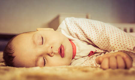 Cute newborn baby sleeping on the bedの写真素材