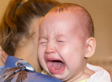 Mom soothes baby. The baby is cryingの写真素材