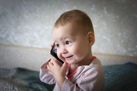 The baby is playing with a smartphoneの写真素材