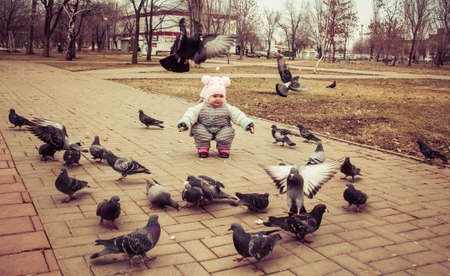 The kid is playing with the pigeonsの写真素材