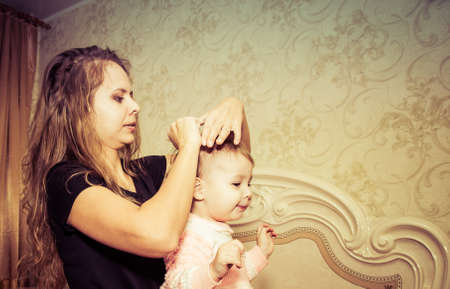 Mom makes a beautiful hairstyle to her daughterの写真素材