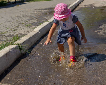 Cute baby sports and runs through the puddles on a summer sunny dayの写真素材