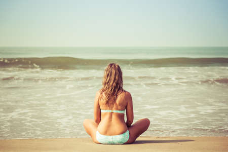 Young woman meditates sitting on the oceanの写真素材