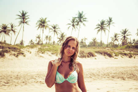 Portrait of a young woman on the beach against the backdrop of palm trees