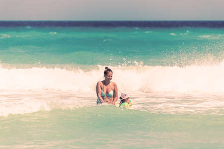 Mom and daughter swim together on the waves, mom teaches daughter to swimの写真素材