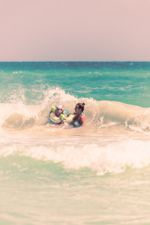 Mom and daughter swim together on the waves, mom teaches daughter to swimの写真素材