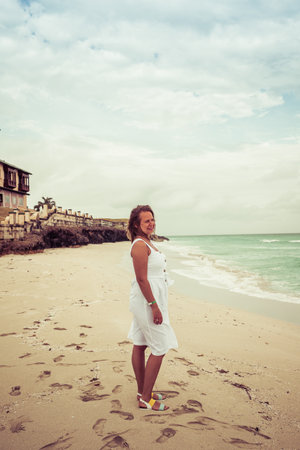 girl in a white dress posing on the background of the oceanの写真素材