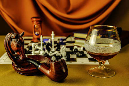 still life with a glass of cognac tobacco pipe tangerines ashtray books and chess on a chessboardの写真素材