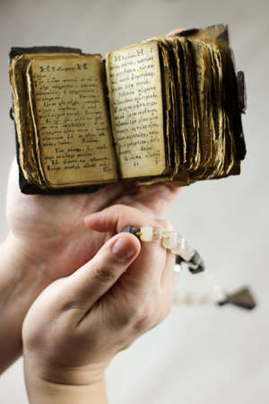 old battered prayer book and rosary in handの写真素材