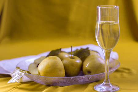 soaked apples on a plate and glass of wine on a tableの写真素材