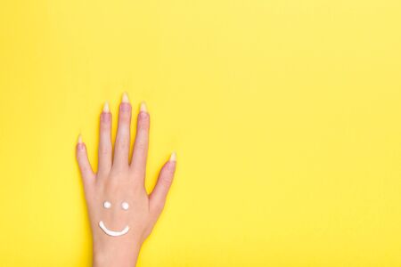 Woman's hand in cream. Yellow background. Girl's hand yellow background. Beauty and health concept of hands. Moisturizing cream for skin care. View from above.の写真素材