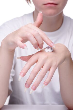 Beautiful hands girl on white background. Beautiful hands of young woman white background. Moisturizer female hand. Apply cream on the skin hands. Applying moisturizer for the hands young girl. の写真素材