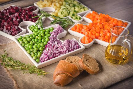 
Delicious fresh pieces of vegetables of carrots, cucumber, potatoes, beets and peas close-up with fresh onion and olive oil on a bag cloth on a rustic gray table.の写真素材