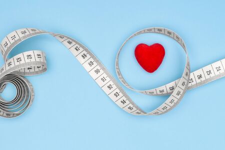 Concept of a healthy lifestyle. Flexible line for fitness.Red heart on a blue background wrapped with a flexible ruler.の写真素材