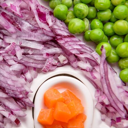 Green peas, carrots cut into cubes and fresh onion turnip cut for salad on a plate close up.の写真素材