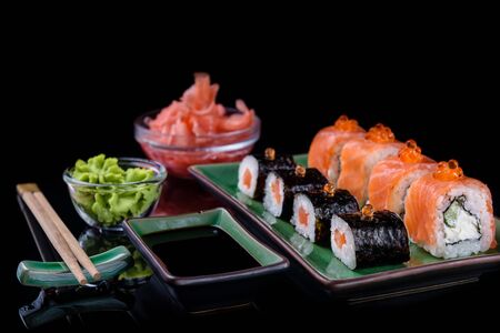 Japanese food. A set of various rolls of salmon, eel, shrimp and red caviar, in a beautiful green bowl, on a black background with reflection.の写真素材
