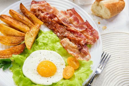 
Fried bacon with French fries and a delicate egg, close-up.の写真素材