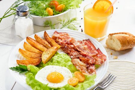 Morning breakfast with delicious fried bacon, French fries and tender egg, close-up.の写真素材