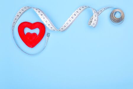 Ð¡oncept of a cure for the heart.Heart, flexible ruler on a blue background as a concept for losing weight and healthy lifestyle.の写真素材