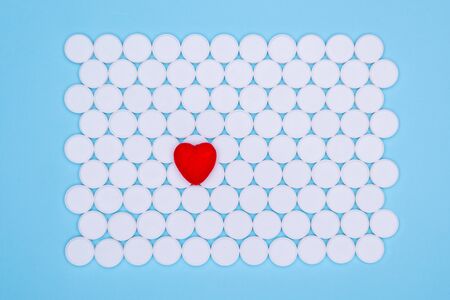 Global healthcare concept. Little red heart. Background of white pills macro with a red heart lying on a blue background, top view.の写真素材