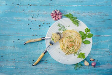 Dish standing on a blue wooden table, a plate with Italian pasta and chicken with a sauce of Provencal herbs, decorated with herbs, salt and garlic.の写真素材