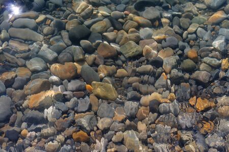 Stones lying in the water. Blue sea water splash. Background of sea water. Natural stone closeup background. Stone pattern.の写真素材