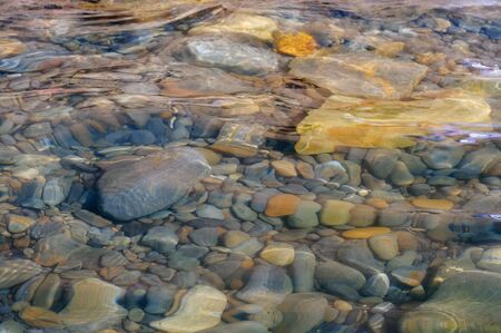 Stones in the water. Blue sea water splash. Background of sea water. Natural stone closeup background. Rough stone background. Stone pattern.の写真素材