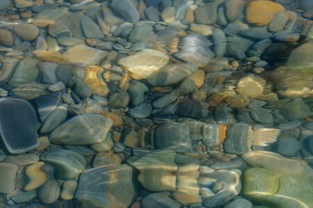 Stones in the water. Blue sea water splash. Background of sea water. A clear splash of water....