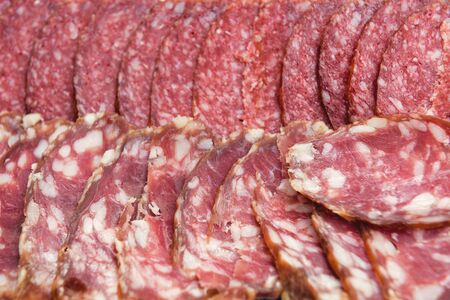Sliced ââdry red sausage with fat and slices of ham cut into thin layers.の写真素材
