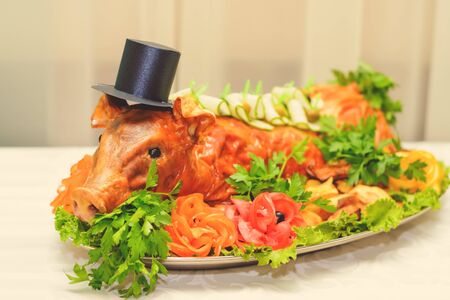 Young fried pig in hat on plate with vegetables.の写真素材