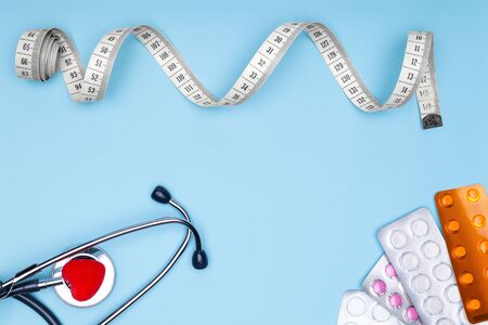 Statoscope, heart, drugs and flexible tape on a blue background. Ð¡oncept of treating cardiovascular diseases.Flexible meter, statoscope and red heart on blue background-concept of sports and fitness.の写真素材