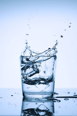 Splashes of clean water in a glass with ice, on a white background.の写真素材