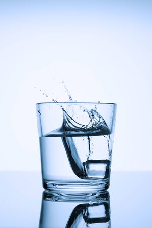Frozen splashes of clean, spring water, in a glass with ice, on a white background.の写真素材