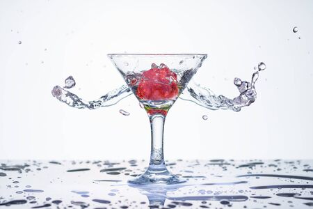 Frozen explosion of freshness from water, in a cocktail glass with strawberries, on a white background.の写真素材