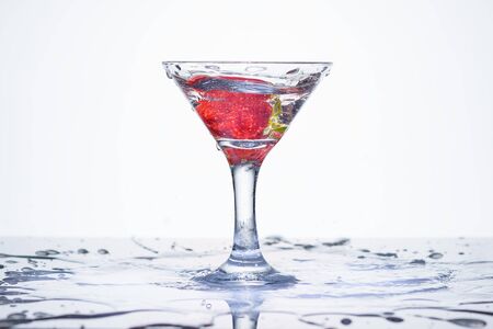 Frozen explosion of freshness from water, in a cocktail glass with strawberries, on a white background.の写真素材
