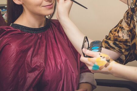 Professional makeup artist applying makeup for young woman in studio.の写真素材
