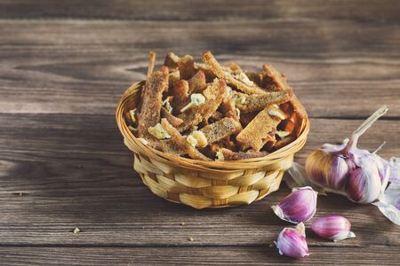 Home snack for beer as rye crumbs with garlic, lying in a wooden table in the rays of sunlight.の写真素材