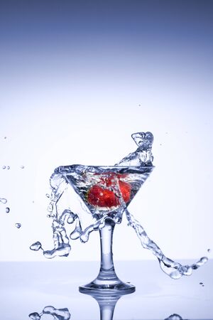 Frozen explosion of freshness from water, in a cocktail glass with strawberries, on a white background.の写真素材