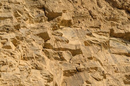 Surface of the rock with a granite stone texture. Designer background for interiors. Stone surface of a yellow texture close-up.の写真素材