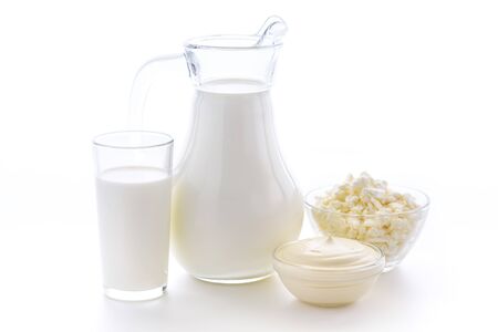 Fresh cow milk in a glass on a white background with a useful curd and sour cream on a white background. Delicious dairy products.の写真素材