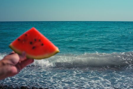 Watermelon, juicy slice in the hands of a woman with over the sea. Diet of tropical fruits.