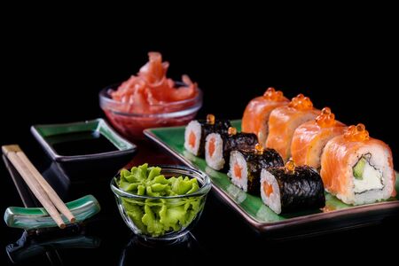 Japanese food. A set of various rolls of salmon, eel, shrimp and red caviar, in a beautiful green bowl, on a black background with reflection.の写真素材