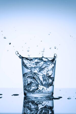 Frozen splashes of clean, spring water, in a glass with ice, on a white background.の写真素材