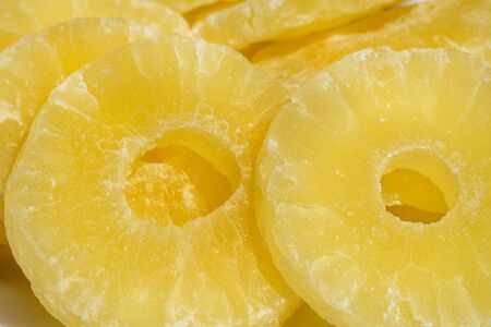 Dried pineapple candy rings, in powdered sugar, close-up in sunlight.の写真素材