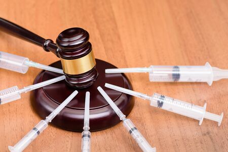  Court hearing against drugs. Medicine and law. Judge's gavel and syringes on a wooden table. The concept of the fight against drugs and drug addiction.の写真素材